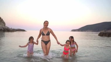 Anne ve kızları sahilde güzel bir gün batımının tadını çıkarıyorlar.