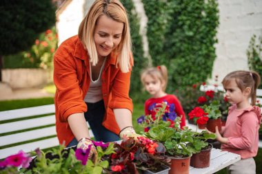 Bir anne çocuklarına çiçek dikmeyi öğretir..