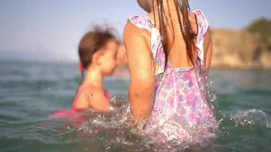 Bir grup çocuk yaz tatilinin tadını çıkarıyor, yüzüyor ve denizde birlikte oynuyorlar.