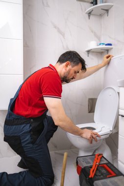 Ev vizitesi sırasında modern bir tuvalette çalışan profesyonel bir tesisatçı.