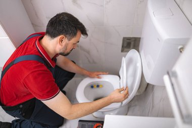 Ev vizitesi sırasında tuvalette çalışan tesisatçı, bakım ve onarım işlerini yapıyor.