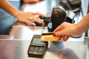 Kasiyer süpermarketteki müşteriden kredi kartı ödemesini kabul ediyor.