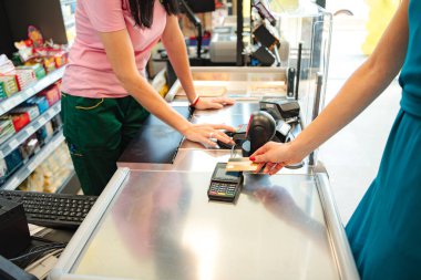 Kasiyer, süpermarketteki müşteriden temassız ödeme kabul ediyor.
