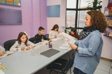 Dil okulunda bir grup ilkokul öğrencisine öğretmenlik yapan bir kadın..