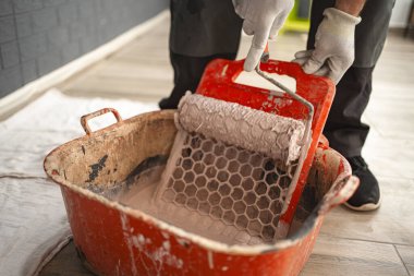 Büyük kırmızı bir kasenin üzerindeki süzgeçte dönen boya silindirinin yakın çekimi..