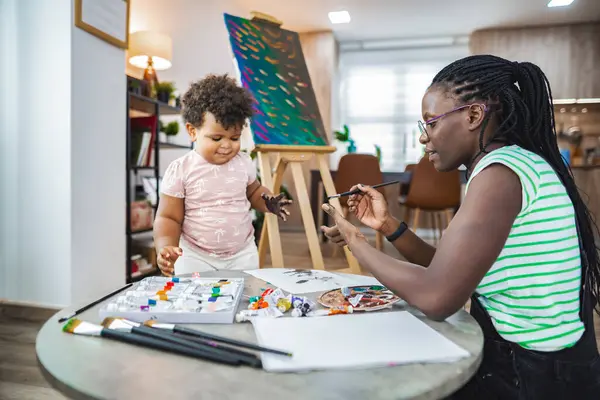Neşeli bir anne renkli bir resim aktivitesinde çocuğuna rehberlik eder..