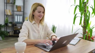 Laptop klavyesinde daktilo eden genç bir kadın, evden uzaktan çalışıyor.