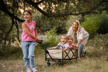 Anne ve kızları doğada at arabasıyla eğleniyorlar.