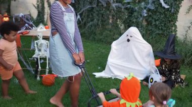 Mother and children playing together in costumes at a Halloween party in the backyard