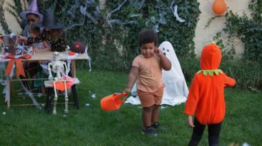 Slow motion of two kids in costumes dancing together at an outdoor Halloween party
