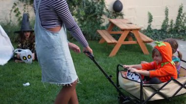 Slow motion footage of a mother pulling a cart with her children in costumes during a Halloween party