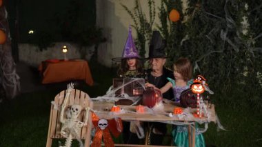Grandmother and her two granddaughters in costumes are enjoying a Halloween party