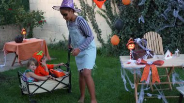 Group of multicultural children in Halloween costumes playing and celebrating in a decorated backyard