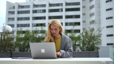 Young businesswoman with a headache working on her laptop on a city rooftop