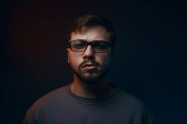 Portrait of a serious young man in glasses on a dark background. High quality photo