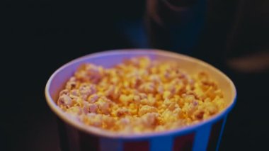 A man is watching a movie and eating popcorn. Popcorn bucket close-up. High quality 4k footage