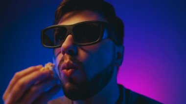 A man in 3D glasses watches a movie and eats popcorn. High quality 4k footage