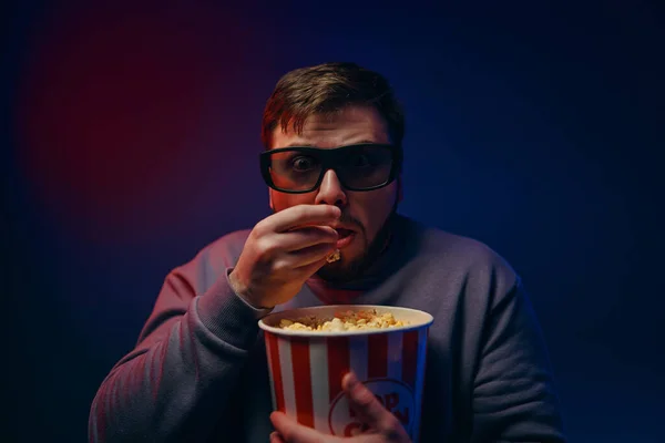 A man is watching a scary movie. Watching a movie with popcorn. High quality photo
