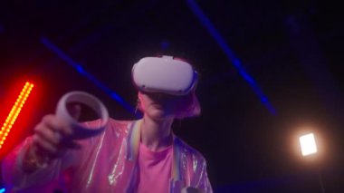 Neon bir odada VR oynayan bir oyuncu. Pembe giysi ve oyuncunun görüntüsü. Parlak efekt. Yüksek kalite 4k görüntü