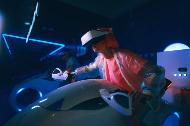 Oyuncu VR 'da motosiklet yarışı oynuyor. Pembe saçlı genç bir kadın oyun oynuyor. Yüksek kalite fotoğraf