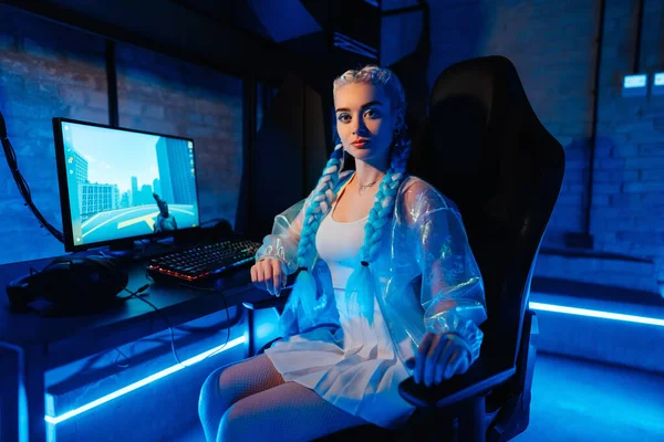 Young female blogger, gamer plays games on computer. Neon computer club. High quality photo