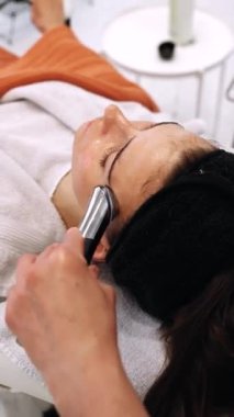 Bir kadın mikro akımlı bir aletle yüzüne masaj yapıyor. Yüksek kalite 4k görüntü