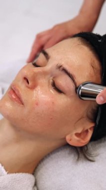 Bir kadın mikro akımlı bir aletle yüzüne masaj yapıyor. Yüksek kalite 4k görüntü