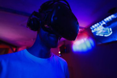 A player plays a game using a virtual reality helmet in a neon room. Close-up photo. High quality photo