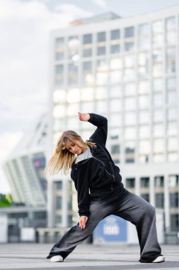 Genç bir kadın büyük kıyafetler giyer ve hip-hop dans eder. Yüksek kalite fotoğraf