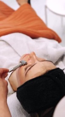 Serumu emmek için bir kadının yüzüne silindirle masaj yapmak. Yüksek kalite 4k görüntü