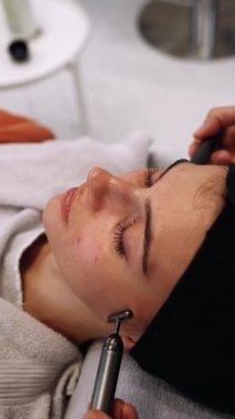 Bir kadın güzellik salonunda yüz masajı yaptırıyor. Usta masaj için aletler kullanır. Yüksek kalite 4k görüntü