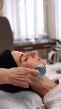 Bir kadın güzellik salonunda yüz masajı yaptırıyor. Usta masaj için aletler kullanır. Yüksek kalite 4k görüntü