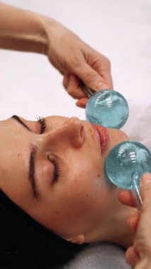Bir kadın güzellik salonunda yüz masajı yaptırıyor. Usta masaj için aletler kullanır. Yüksek kalite 4k görüntü
