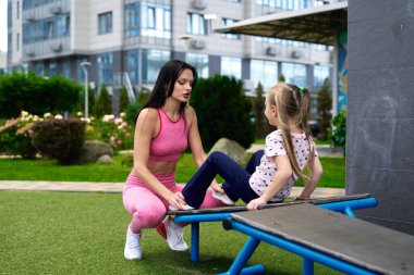 Yeşilliklerle çevrili bir spor salonunda spor salonunda bir kadın bir çocuğa rehberlik ediyor..