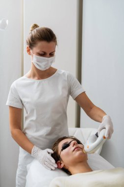 Anestezi uzmanı cilt bakımı yaparken hasta tedavi yatağında dinleniyor..