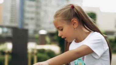 Genç bir kız açık havada oynamaktan, canlı bir şehir parkında çevresini keşfetmekten hoşlanıyor..