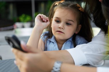 Bir kız akıllı telefon ekranını dikkatle izliyor, merak ve nişanı gösteriyor..