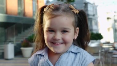 Neşeli bir çocuk açık havada güneşli bir günün tadını çıkarır, şehir ortamında neşe saçar..