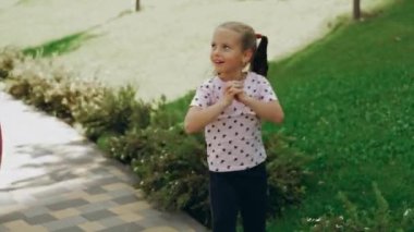 Genç bir kız güneşli bir öğleden sonranın tadını çıkarırken yeşil bir parkta neşeyle oynuyor..