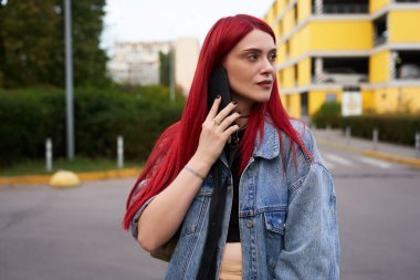 Genç bir kadın dışarıda dururken akıllı telefonunu kontrol ediyor..