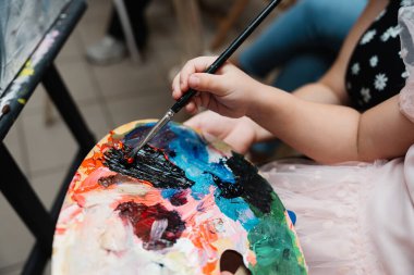 Genç bir sanatçı canlı bir palette fırçayla boya uygular..