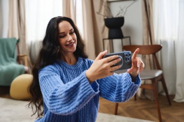 Bir kadın evde dinlenirken telefonuyla selfie çekmekten hoşlanır..