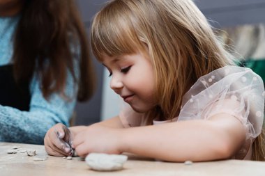 Küçük bir kız içeride sanatsal faaliyetlerin keyfini çıkarırken killeri şekillendirmeye odaklanmış..