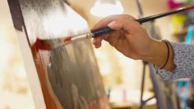 Bir sanatçı ustalıkla parlak bir stüdyodaki tuvale boya sürer..