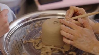 Bir insan geleneksel çömlek tekniklerini kullanarak kilden bir kaba şekil verir..
