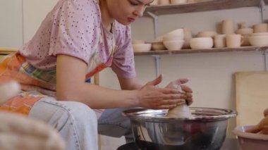 Bir acemi, balçığı davetkar bir çalışma alanında güzel bir çömlek haline getirir..