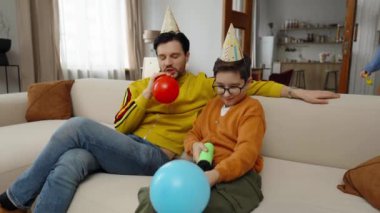 Partiye katılanlar şapkalarını takıp renkli balonlar şişiriyorlar..