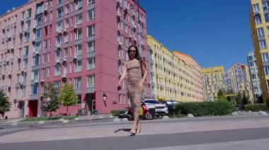 Bir kadın modern mimariyle canlı bir mahallede zarifçe dolaşır..