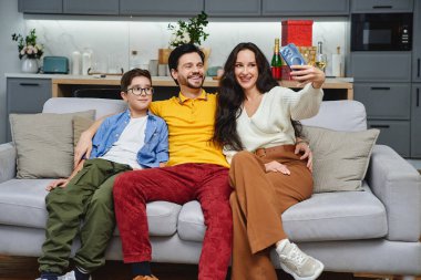 Mutlu bir aile kanepede oturup neşeli bir selfie çekiyor..