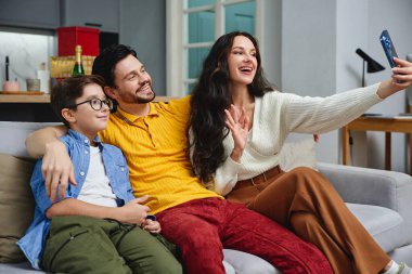 Aile bireyleri birlikte selfie çekerken gülümseme ve kahkaha atarlar.